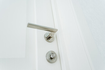 Bottom view of the doorknob in the room, locked door, chrome hardware.