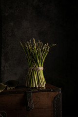 Fresh stems of green asparagus on dark wooden background. Macro view, copy space. Vegan, healthy...