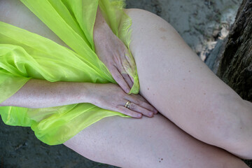 close-up view of the thighs of a lying sexy woman covered with light green cloth