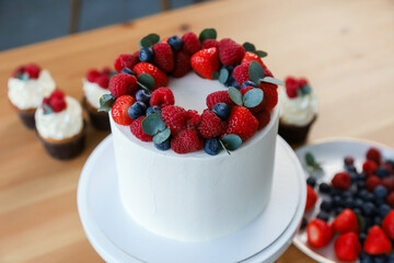 white cake with red raspberries and strawberries in the kitchen