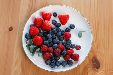 a plate with blueberries, strawberries and raspberries, top view