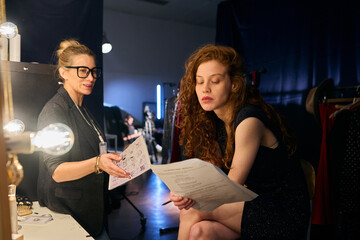 Portrait of female director and actress practicing script lines backstage in theater copy space