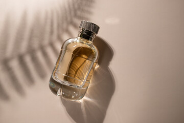 Golden perfume with leaf shadow on beige background, transparent spray bottle, sensual aroma,...