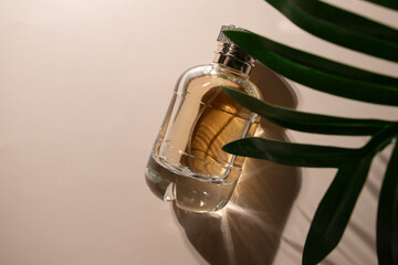 Golden perfume with palm leaf on beige background, glamorous glass bottle, floral fragrance, luxurious packaging