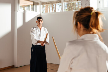 Female Martial Artist Engages In Bokken Sword Practice With Partner In Dojo