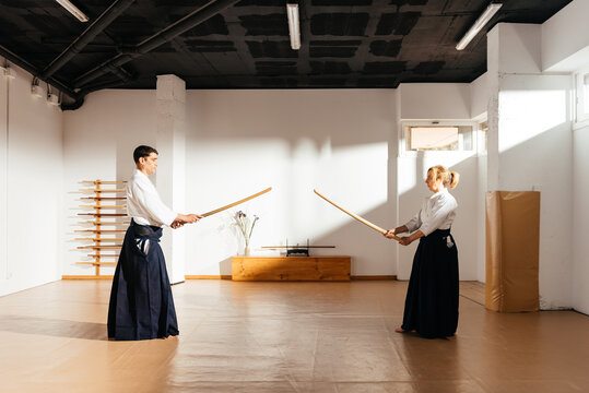 Two Martial Artists Engaging in Sword Practice at a Dojo During Daylight