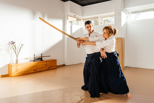 Man and Woman Practicing Martial Arts With Bokken Defense - Powered by Adobe