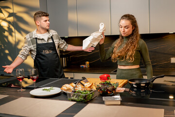 young couple in love in beautiful kitchen cooking together conflict negative mood quarrel