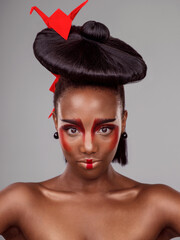 Portrait, makeup and black woman with origami for beauty in studio isolated on gray background....