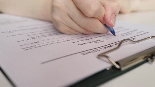 Affidavit of small estate, hand fills out a document, contract signing, house purchase, financial planning.