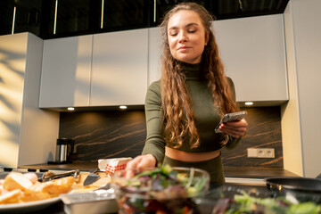 a young girl in love in a green dress in the kitchen preparing dinner according to a recipe from...