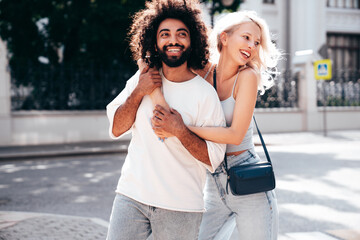 Smiling beautiful woman and her handsome boyfriend. Woman in casual summer jeans clothes. Happy cheerful family. Female having fun. Sexy couple posing in the street at sunny day. Embracing each other