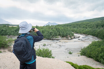 Rivers at Valley of Ten Thousand Smokes. Woman taking photos using smartphone.