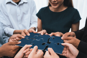 Diverse corporate officer workers collaborate in office, connecting puzzle pieces to represent...