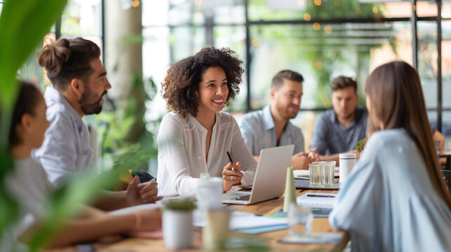 At a communal workbench in a collaborative workspace, a young female HR manager meets new employees for a casual introduction, her approachable nature and open communication style