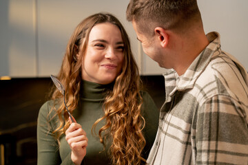close up young couple in love in beautiful kitchen preparing dinner joking playing flirting feeding...