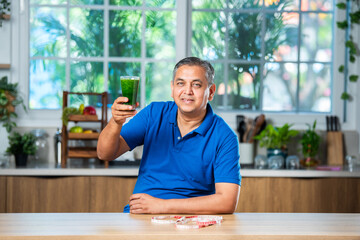 Asian Indian man in 40s having fresh freen juice in a glass