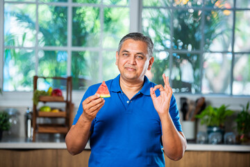 Indian asian man eating watermelon slice or tarbuj at home