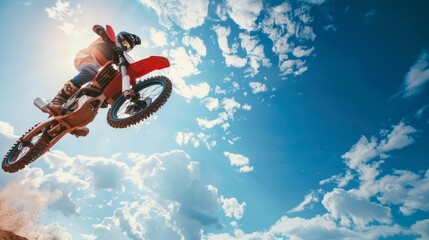 A close-up shot capturing a motocross rider launching off a dirt ramp, with the bike suspended mid-air in a thrilling moment