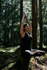 A young woman does yoga and meditates in the forest. Yoga and meditation concept. Yoga asanas. 