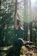 A young woman does yoga and meditates in the forest. Yoga and meditation concept. Yoga asanas. 