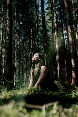 Naklejka premium A young woman does yoga and meditates in the forest. Yoga and meditation concept. Yoga asanas. 