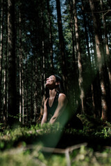 Naklejka premium A young woman does yoga and meditates in the forest. Yoga and meditation concept. Yoga asanas. 
