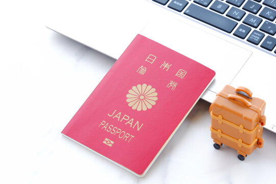 日本のパスポート（一般旅券10年用赤色）とスーツケースで、海外旅行に出発するイメージ
