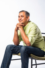 Handsome indian asian mid age man sitting on chair and relaxing