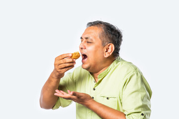 Indian asian handsome man in 40s eats tasty golgappa against white background