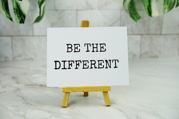 Be the Different text message on paper card with wooden easel Positive inspirational quote