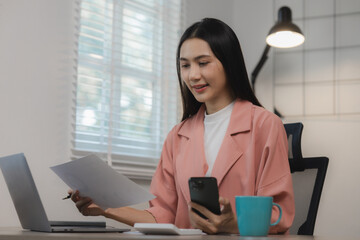 A beautiful Asian woman was happily sitting in her private office in an atmosphere filled with happiness as an assignment was being completed and completed successfully.