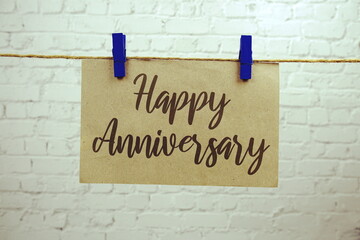 Happy Anniversary text on paper card hanging on the wall with Clothespins