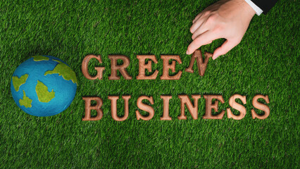 Businessman's hand arrange message in Green Business as concept of corporate effort to commitment...