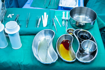 Disinfectant cup set for prepare breast surgery.Plastic surgeon sewing up breast of female patient after inserting implants in operating room.Medical team performing surgery in operation room.