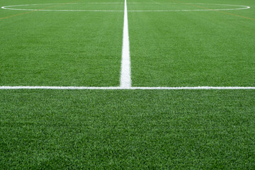 Close-up of a soccer field with green, well-maintained artificial synthetic grass painted with...