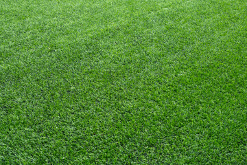 Close-up background texture of new and clean synthetic lawn or artificial grass surface for ground covering.