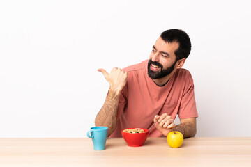 Caucasian man having breakfast in a table pointing to the side to present a product.