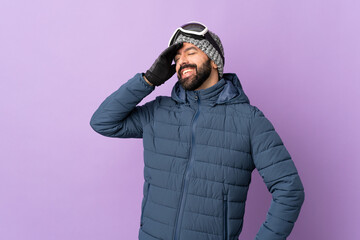 Skier man with snowboarding glasses over isolated purple background smiling a lot