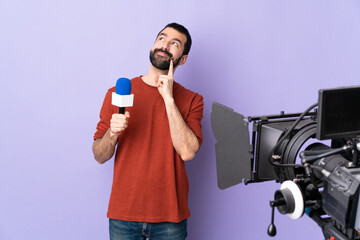 Reporter man holding a microphone and reporting news over isolated purple background thinking an...
