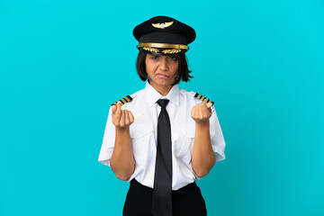 Young airplane pilot over isolated blue background making money gesture but is ruined