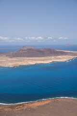 Views of the island of La Graciosa from the viewpoint of El Rio. Turquoise ocean. Blue sky with big white clouds. Caleta de Sebo. Town. volcanoes. Lanzarote, Canary Islands, Spain