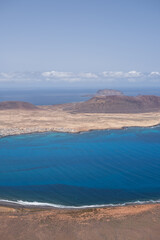 Views of the island of La Graciosa from the viewpoint of El Rio. Turquoise ocean. Blue sky with big white clouds. Caleta de Sebo. Town. volcanoes. Lanzarote, Canary Islands, Spain