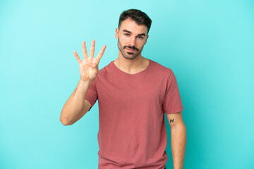 Young caucasian man isolated on blue background happy and counting four with fingers