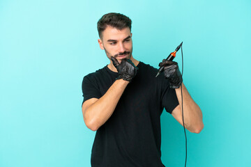 Young tattoo artist man isolated on blue background looking to the side and smiling