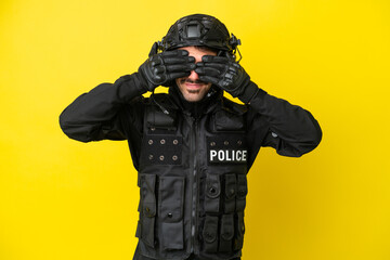 SWAT caucasian man isolated on yellow background covering eyes by hands