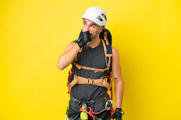 Young caucasian rock climber man isolated on yellow background having doubts and with confuse face...