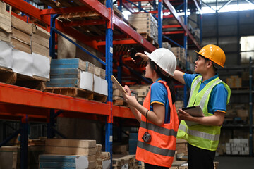 Two warehouse workers do a stocktaking of product management on shelves in the warehouse. Physical...