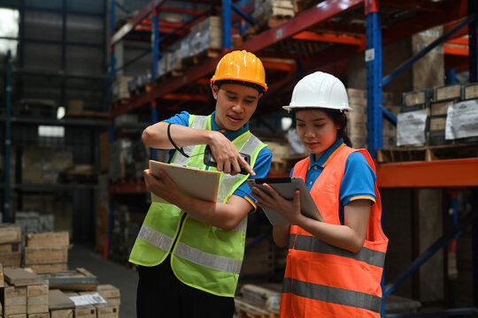 Two warehouse workers using digital tablets to check the stock inventory on shelves in warehouses, a warehouse management system, supply chain, and logistic network technology concept