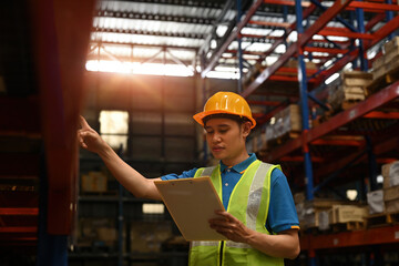 A male warehouse employee checks and counts the stock inventory on a clipping board, a Warehouse...